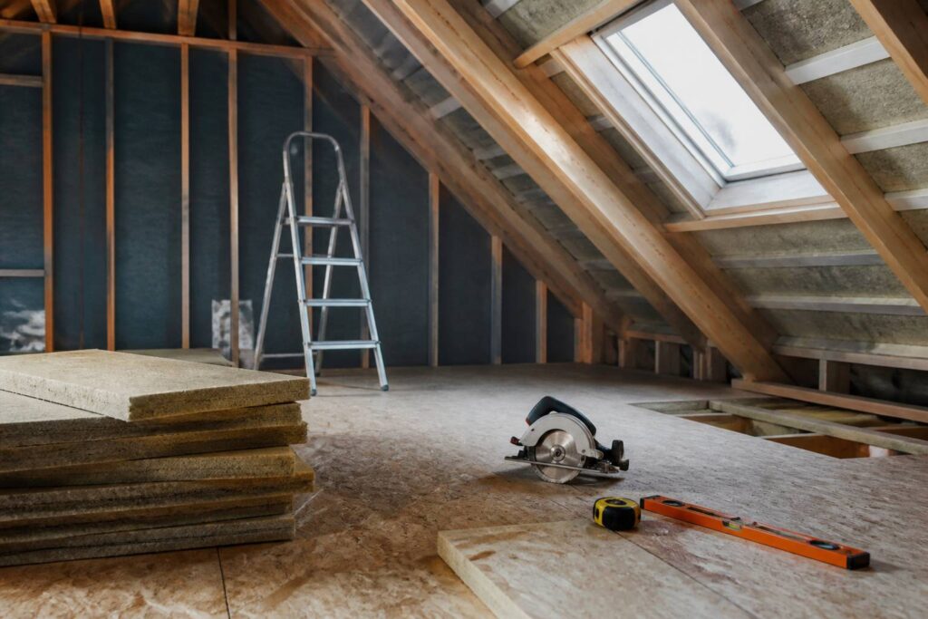 Chantier de combles avec plancher OSB posé sur solives, mètre ruban et niveau à bulle