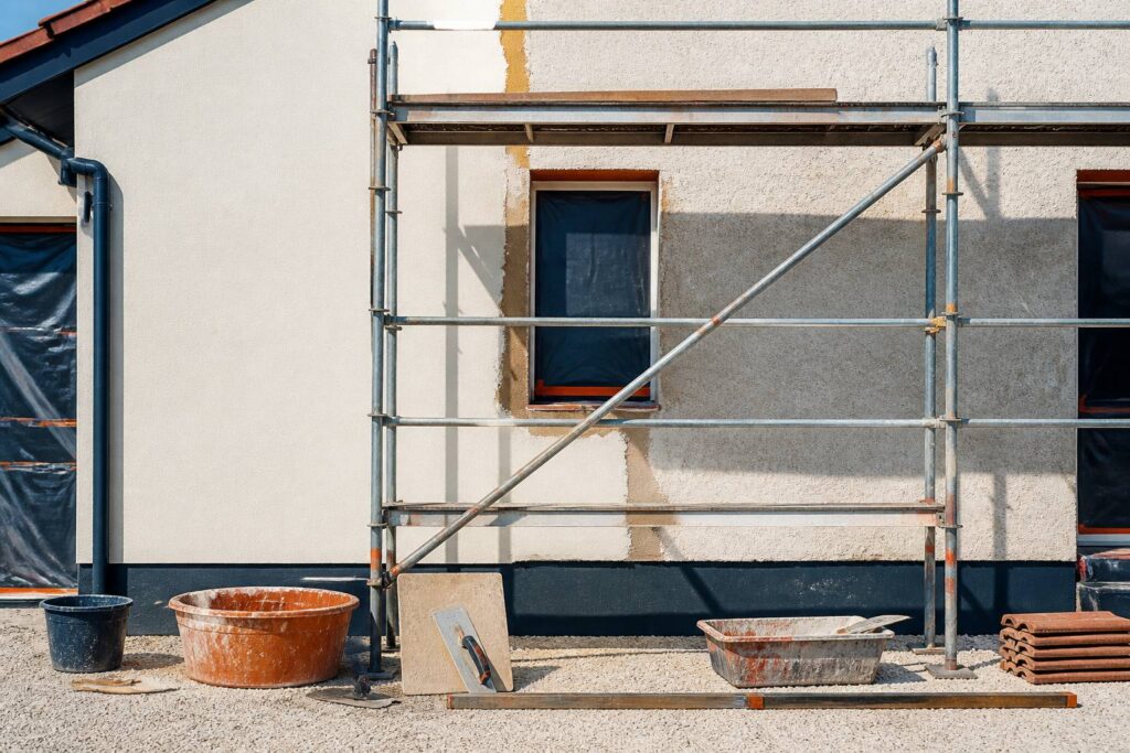 Façade de maison en rénovation avec échafaudage et enduit frais partiel