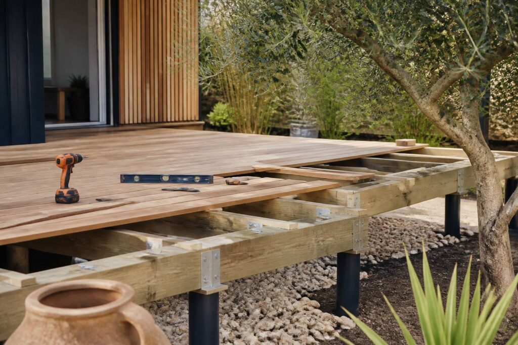 Terrasse en bois sur pilotis en cours de construction dans un jardin avec la structure visible