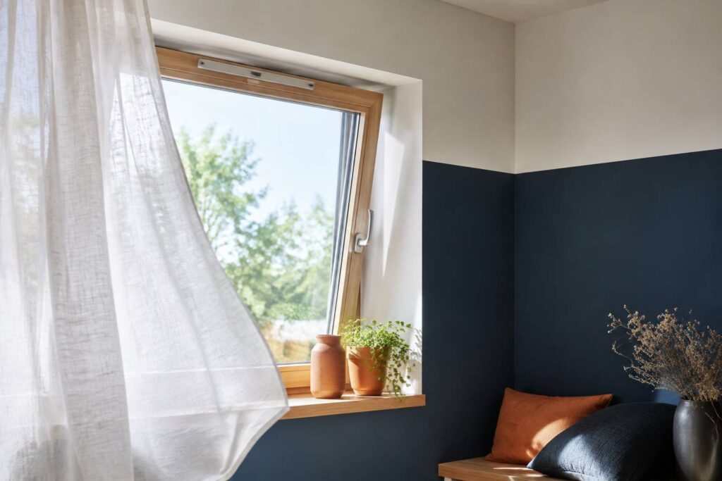 Fenêtre entrouverte avec entrée d'air en partie haute dans un intérieur clair et aéré